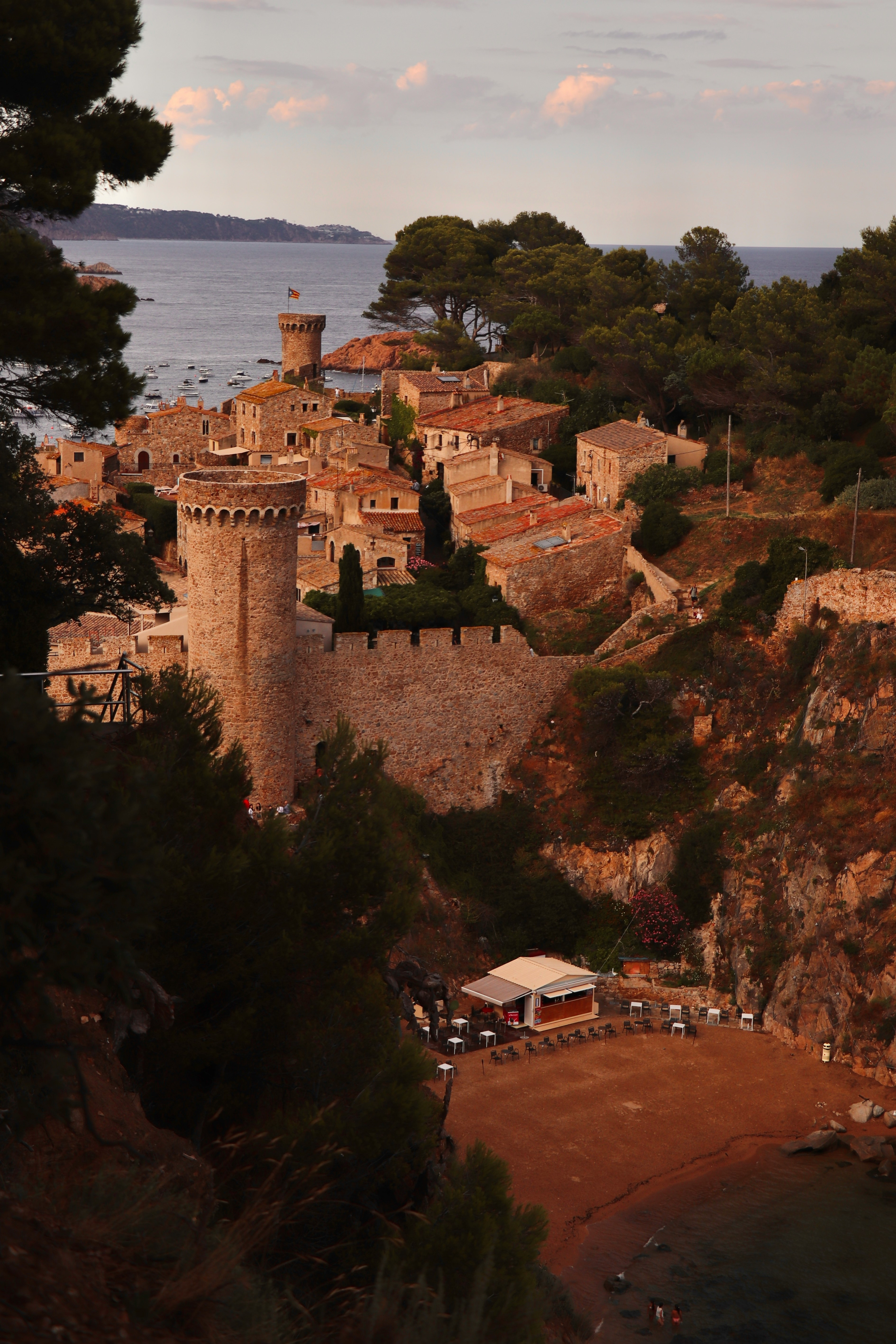 A stone-walled Mediterranean village on a coastal headland at dusk